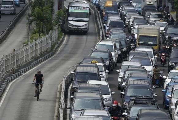 biker breezes past traffic a bicycler enjoys a benefit of biking by pedaling around a traffic jam