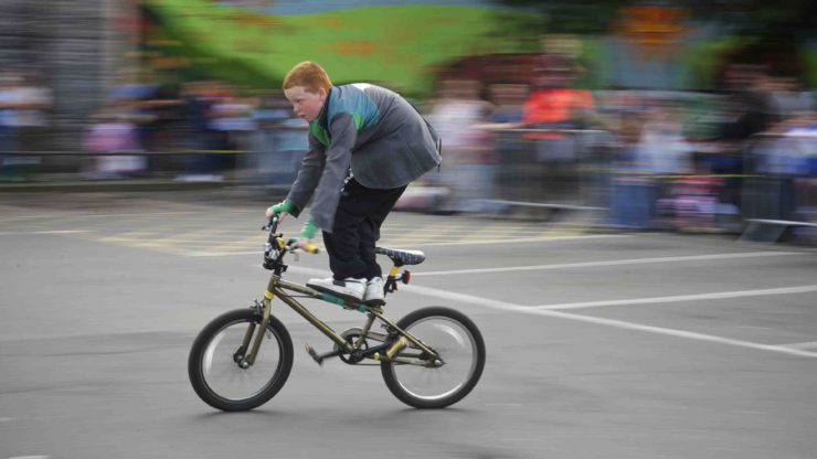 boy riding bike standing up a boy stands on his bicycle showing improved balance as a benefit of biking