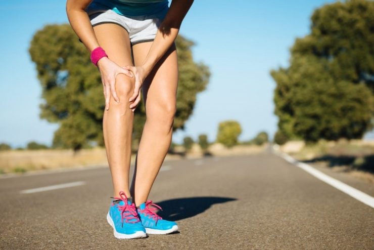 runner holding knee avoiding knee pain while running is a health benefit of biking
