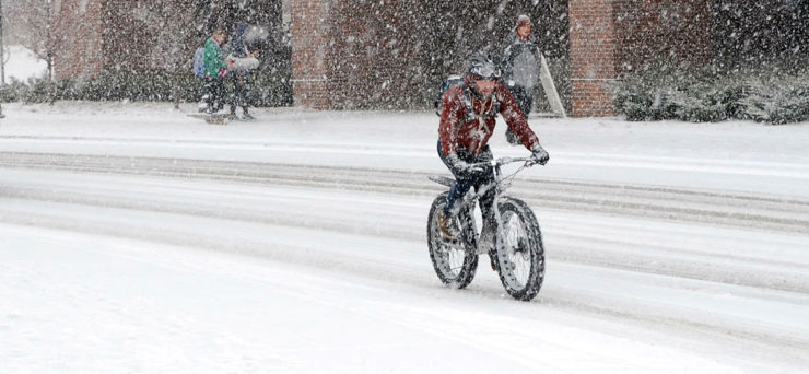 winter biker a bicycler riding in the snow shows that health benefits of bicycling are year round